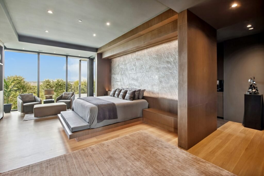 A bright bedroom with a low bed, large windows and a standing lamp