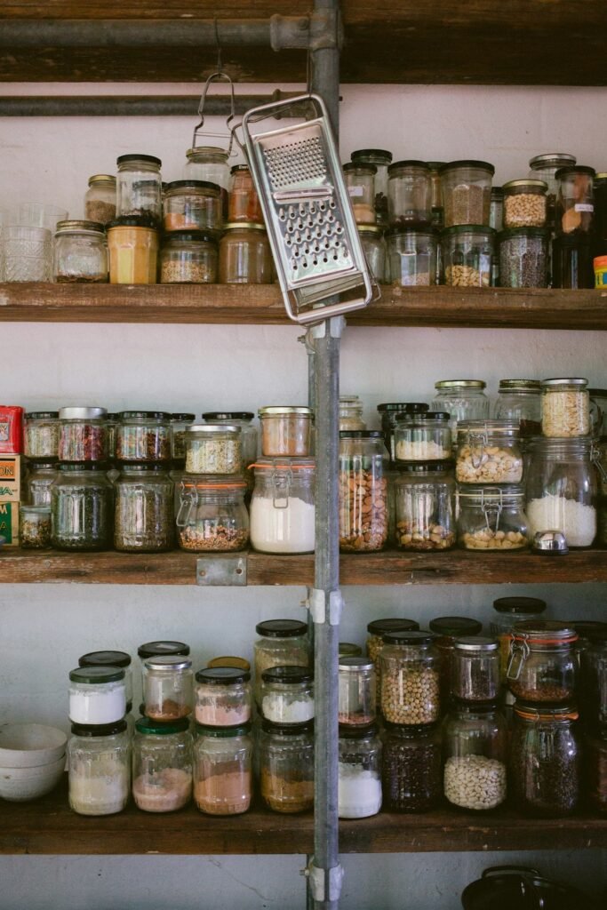 Glass jars of dry ingredients arranged on open kitchen shelves
