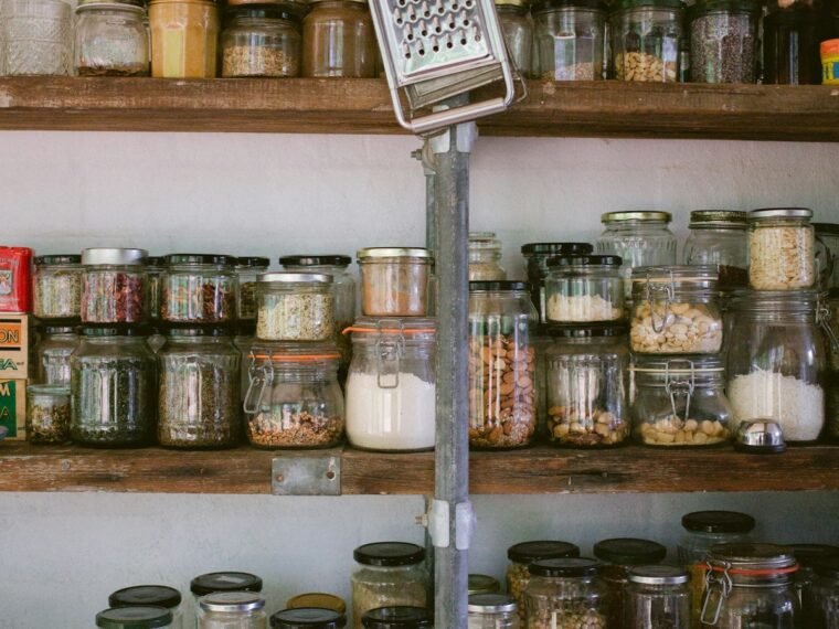 Glass jars of dry ingredients arranged on open kitchen shelves